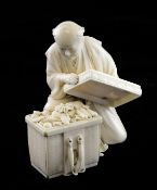 A Japanese ivory figure of a man opening a box of objects, Meiji period, the man kneeling on his