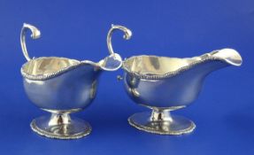 A pair of George III style silver pedestal sauceboats, with flying scroll handles and oval feet,