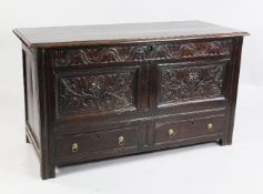 An 18th century carved oak mule chest, with twin panelled front and frieze carved with stylised