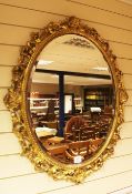 An oval gilt florentine style wall mirror, pierced with scrolling acanthus decoration, L.2ft 9in.