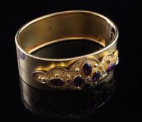 A Victorian gold and garnet hinged bangle, the central motif set with eleven oval and round cut