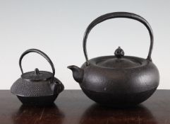 Two Japanese iron teapots, 19th century, the first of compressed globular form with a high looped