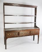 An 18th century oak dresser, with open plate rack with cup hooks, above three frieze drawers, on