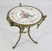 A late Victorian circular brass occasional table, the top inset with a floral painted porcelain