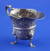 A George III Irish silver helmet cream jug, with scroll handle, repousse scroll decoration and pad