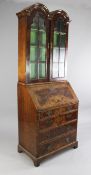 A Queen Anne style walnut bureau bookcase, with double domed top over two glazed doors, above a