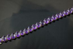 A 14ct gold and amethyst line bracelet, set with twenty oval cut amethysts, 6.75in.