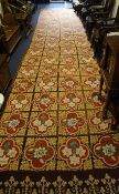 An Aubusson style tapestry runner, decorated with four rows of seventeen floral panels, on a brown