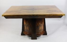 An Art Deco figured walnut and rosewood dining table, the rectangular top on an oval pedestal base,