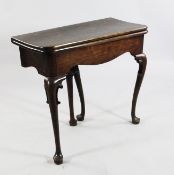 A mid 18th century mahogany folding tea table, with serpentine frieze, on scroll carved cabriole