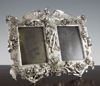 An Art Nouveau silvered pewter double photograph easel frame, with central winged figure and floral