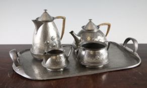 A Liberty & Co pewter four piece teaset, with raised stylised floral decoration and wicker handles,