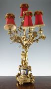 A Victorian ormolu six branch candelabra, with a seated cherub holding aloft floral scrolling