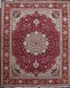 A Tabriz part silk carpet, with central foliate medallion in a field of scrolling foliage, on a red