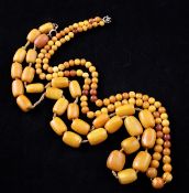 Two single strand amber bead necklaces, graduated round bead and barrel shaped, both with clasps,