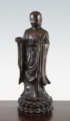 A Chinese bronze standing figure of a luohan, Qing dynasty, holding a flaming pearl in his left