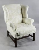 A George III style wingback armchair, with scroll arms, moulded legs and cream damask upholstery