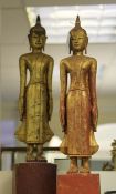 A pair of Thai carved giltwood and polychrome standing figures of Buddha, each on a rectangular