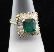 An 18ct gold emerald and diamond cluster ballerina ring. the central emerald bordered by trapeze cut