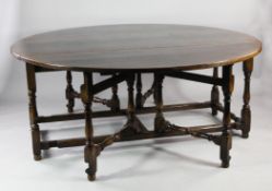 A large 18th century style oval oak gateleg table, on turned supports united by stretcher, extends