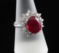 A 14ct white gold oval cut ruby and diamond cluster ring, the ruby weighing 6.50ct and bordered with