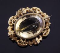 A Victorian gold and citrine brooch, with oval cut stone and ornate scroll border, 2in.