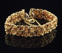 A Far Eastern high carat gold articulated bracelet, with pierced foliate scroll links and coin set