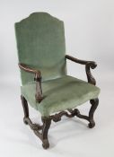 A Louis XIV style carved oak open armchair, with scroll arms and legs and green upholstery