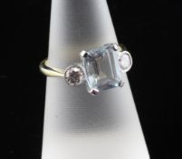 An 18ct gold, aquamarine and diamond ring, the emerald aquamarine flanked by round cut diamonds,