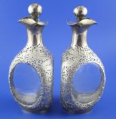 A pair of early 20th century Chinese silver overlaid moulded glass triple lipped decanters and