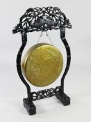 A Chinese bronze dinner gong with ebonised wood stand, early 20th century, the stand carved and