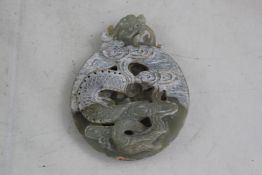A Chinese celadon and calcified jade disc, carved in high relief and open work with a scrolling