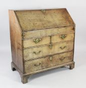 An early 18th century oak bureau, the fall front revealing sliding well and stepped interior over