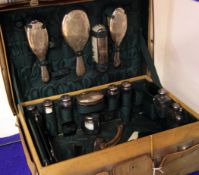 An Edwardian travelling toilet case with fourteen silver mounted items, including jars, brush set