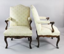 A pair of 18th century Italian carved walnut open armchairs, with serpentine over stuffed seats