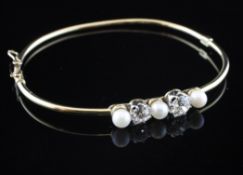 A gold, diamond and cultured pearl hinged bangle, set with two round cut diamonds and three cultured