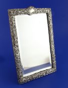 A late Victorian silver mounted dressing table easel mirror, with bevelled glass and repousse border