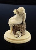 A 19th century carved ivory figure of a girl seated on a basket playing with a cat, on oval base,