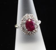 An 18ct gold, ruby and diamond cluster ring, the oval cut ruby weighing approximately 1.25ct and