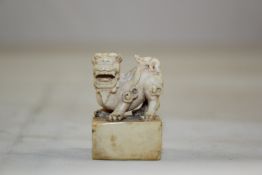 A Chinese ivory seal, 19th century, the rectangular seal surmounted with the figure of a lion-dog,
