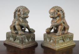 A pair of Tibetan bronze figures of temple lions with plinths, 20th century, one lion with a paw