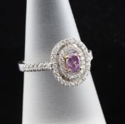 A white gold, pink/purple and white diamond set oval cluster ring, with diamond set shoulders and