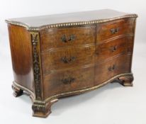 A George III style walnut cabinet, modelled as a serpentine commode, the two cupboard doors with