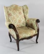 An 18th century Italian carved walnut wingback armchair, with heavy scrolling arms, with shell