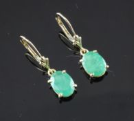 A pair of 14ct gold and emerald set drop earrings, set with oval cut emeralds, 0.75in.