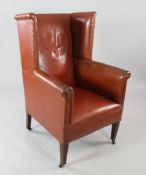 A wingback armchair, with brass studded upholstery, on square section tapering supports and castor