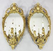 A pair of Victorian carved giltwood oval girandoles, with acanthus scroll crests and three scrolling