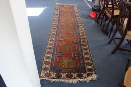 A Turkish runner, with field of nine octagons, on a coral ground, multi flower head border, 12ft 5in