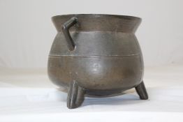 A 17th century bronze cauldron, with angular twin handles, on three feet, 2.5in.