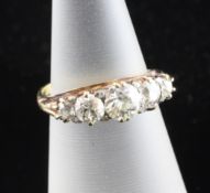 A late Victorian 18ct gold graduated five stone diamond half hoop ring, with carved scroll